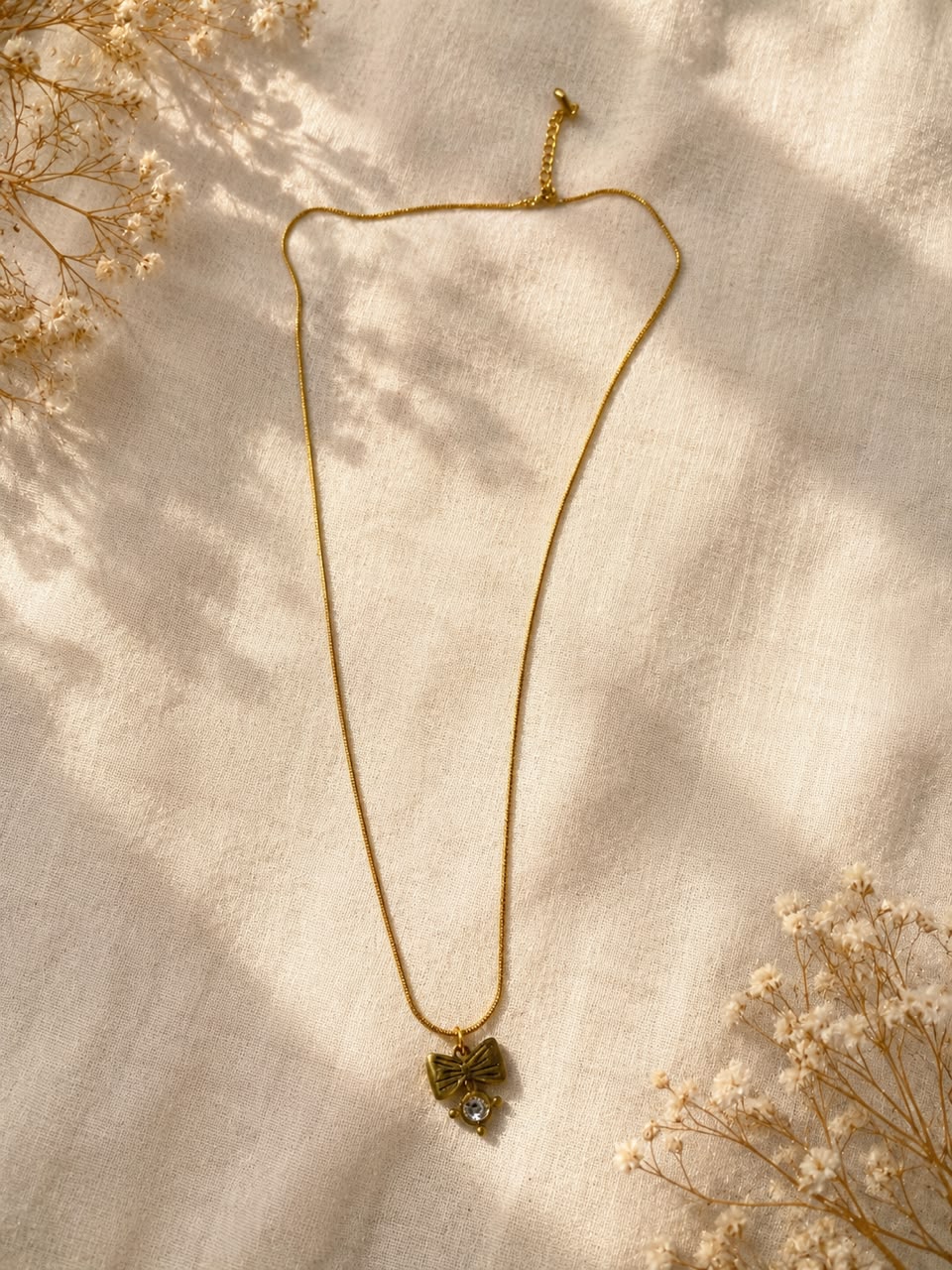 The necklace shown features a gold-toned slim chain paired with a unique decorative pendant.