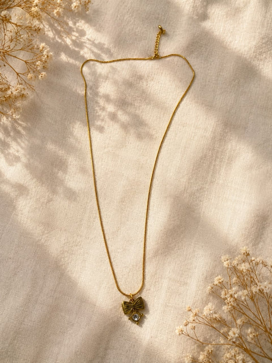 The necklace shown features a gold-toned slim chain paired with a unique decorative pendant.
