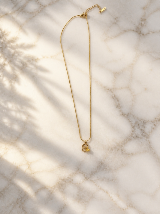 gold-toned necklace featuring a minimalist chain and a unique charm pendant.