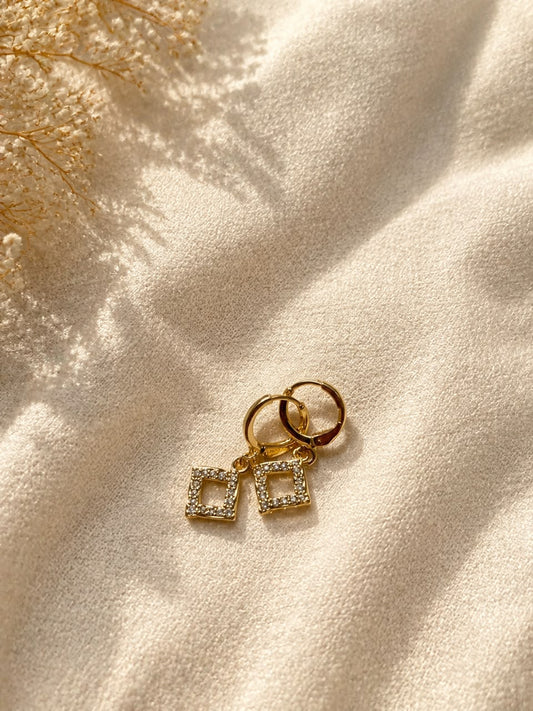 These elegant earrings feature a geometric design with a classic gold-tone finish and sparkling accents.